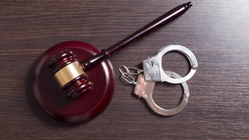 A gavel and handcuffs on a wooden surface.